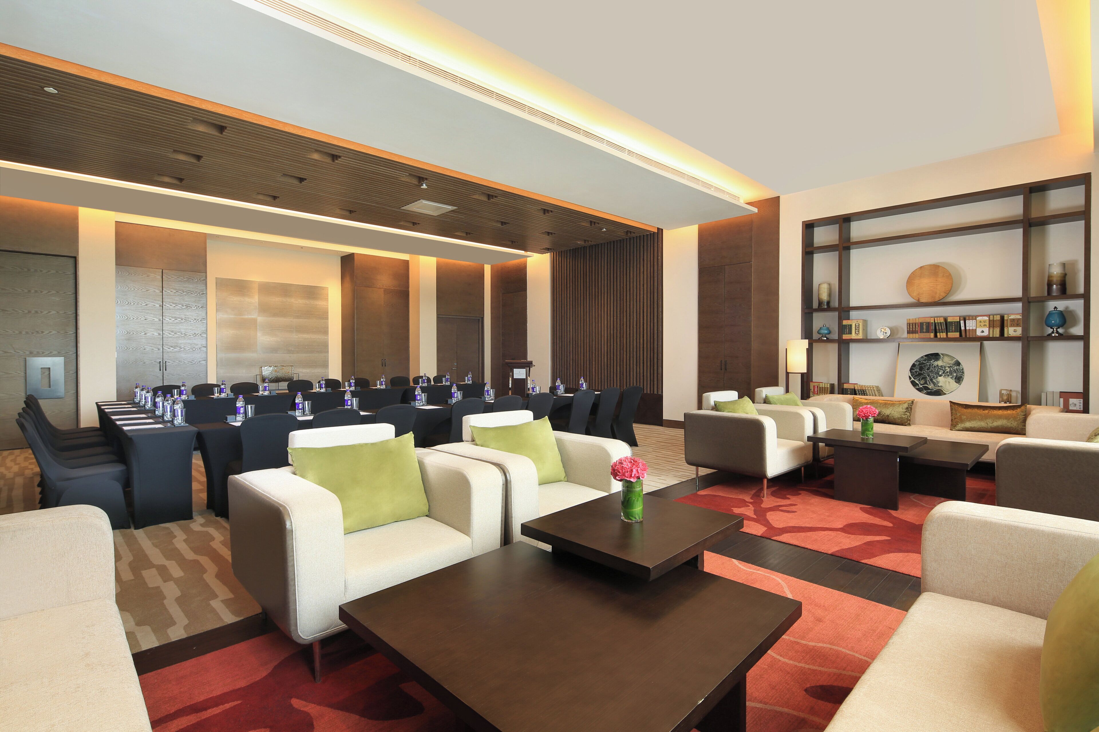 A hotel lobby with a conference room, seating area, and a reception desk.