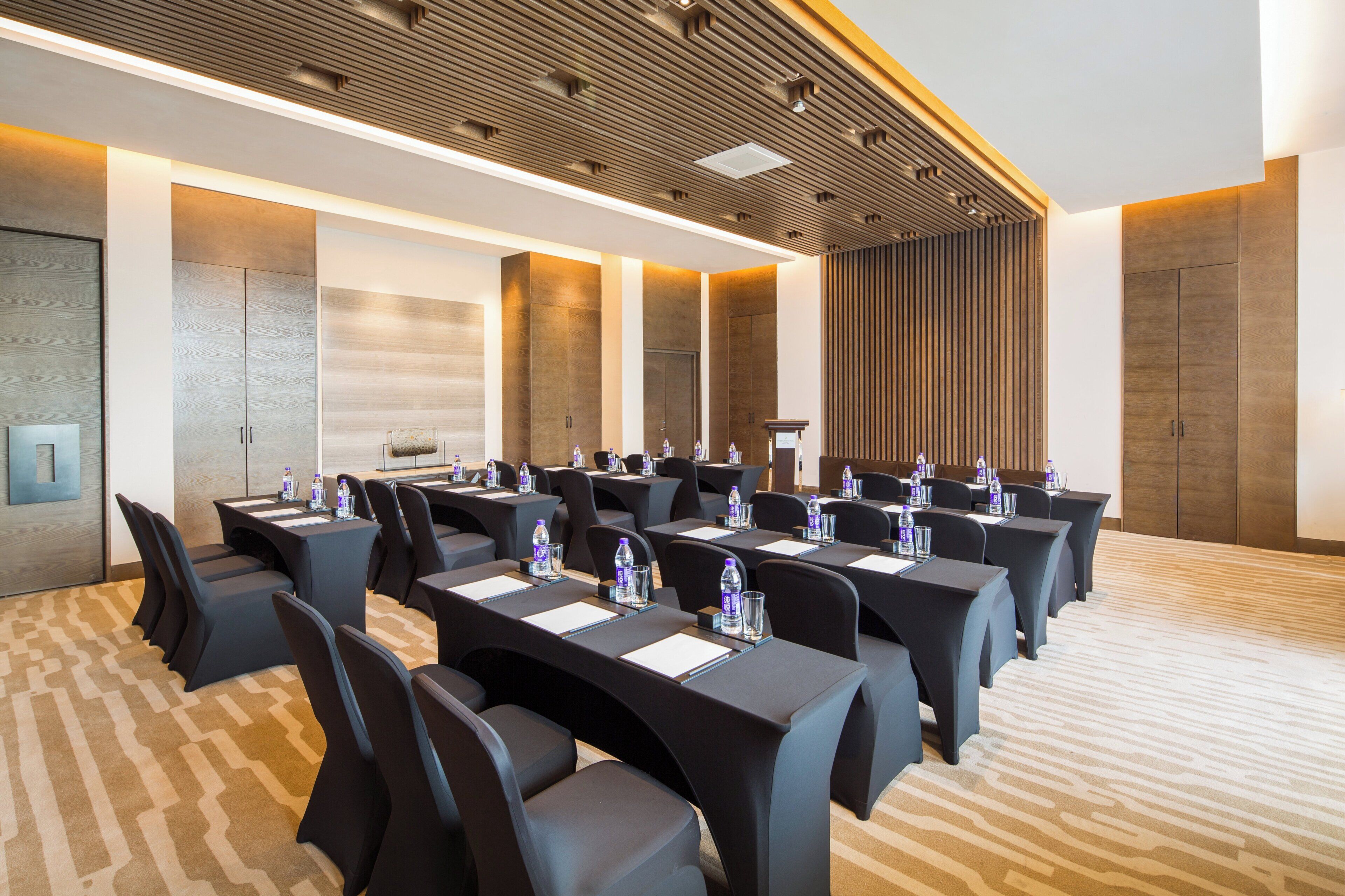 A conference room with multiple tables and chairs, equipped with water bottles and nameplates.