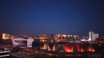 A cityscape at night with illuminated buildings and a modern structure with red curtains.