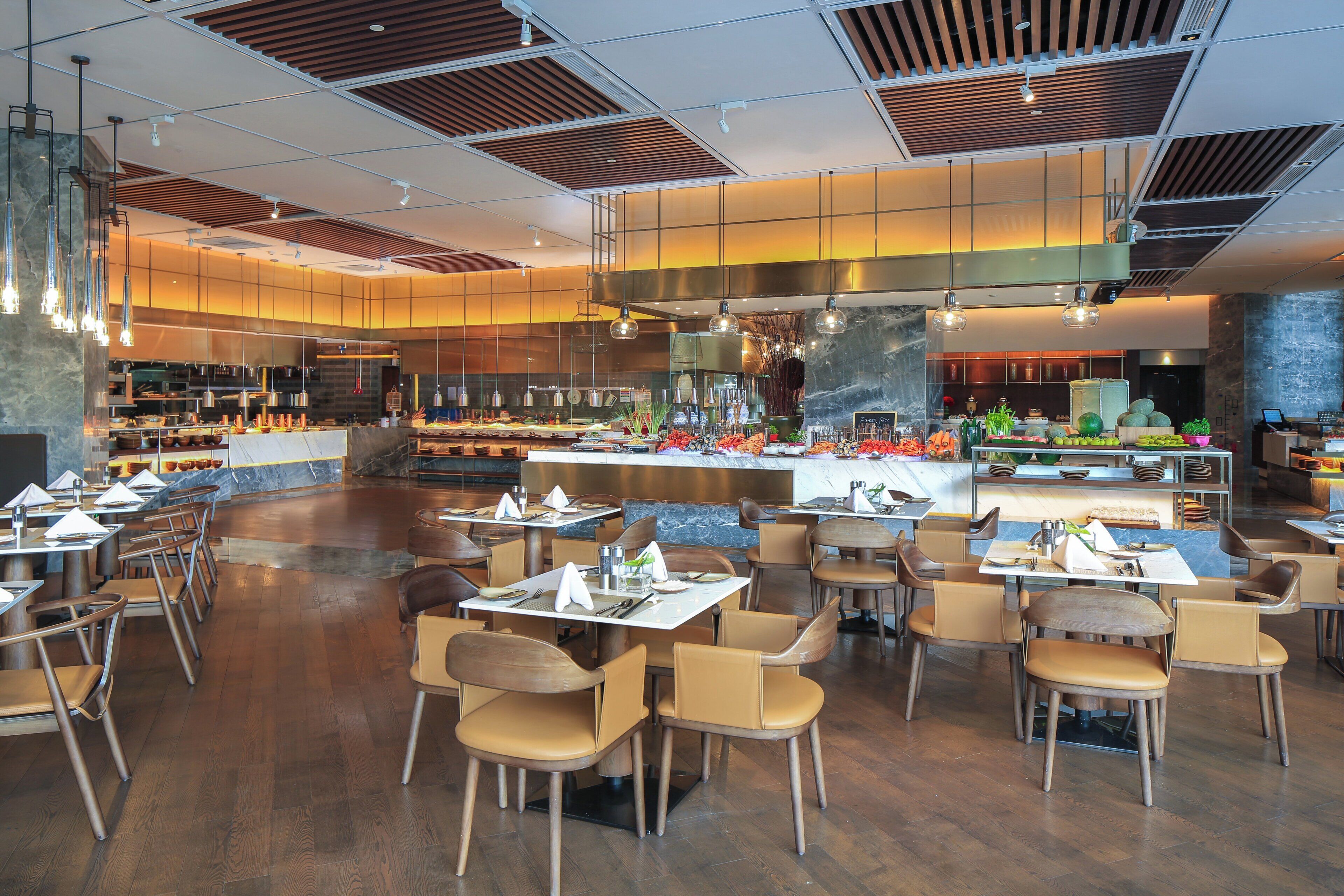 A modern restaurant with a central bar area, multiple dining tables, and a variety of seating options.