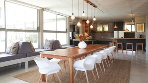 Een moderne keuken met een houten eettafel, witte stoelen en hanglampen.