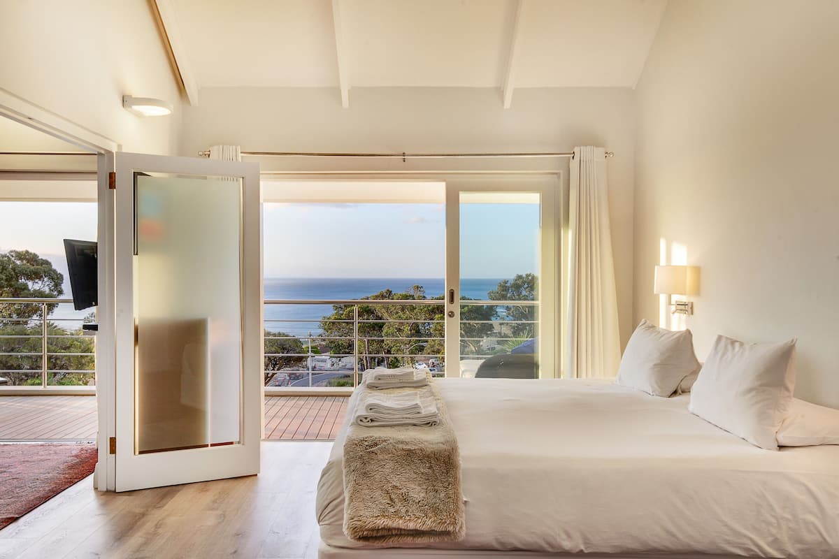 A hotel room with a large bed, a TV, and a view of the ocean.