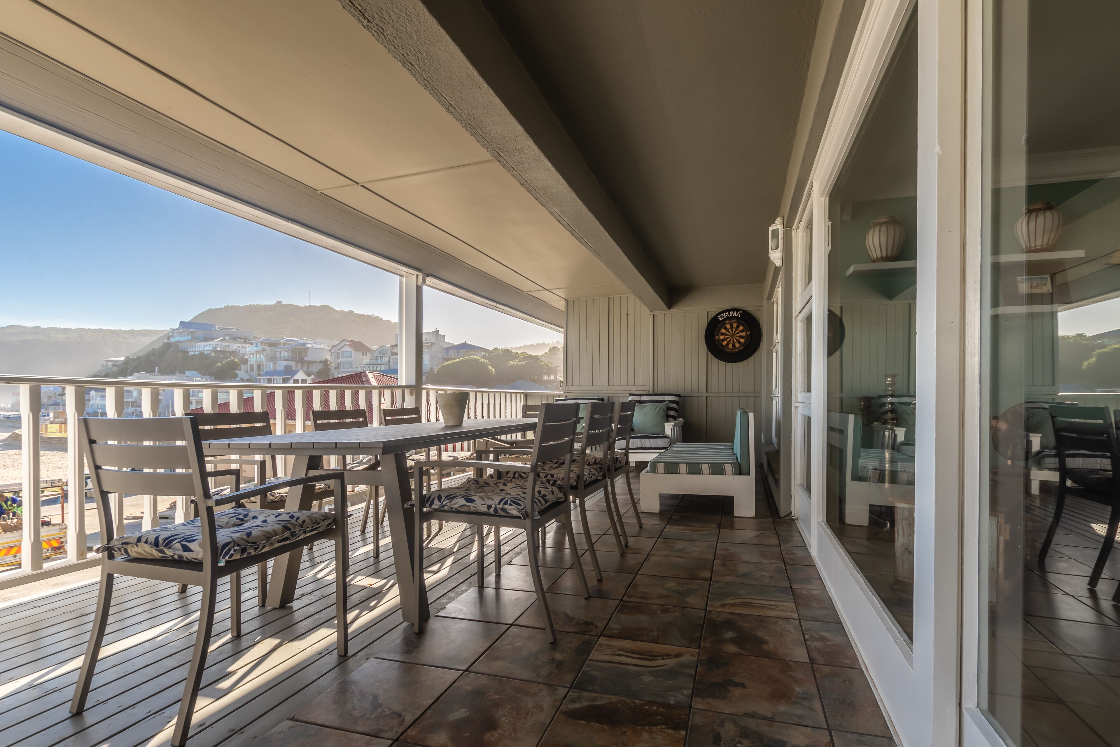 A balcony with a table and chairs, a sofa, and a dartboard.