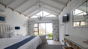 A bedroom with a bed, a TV, a bench, and a view of the outdoors.