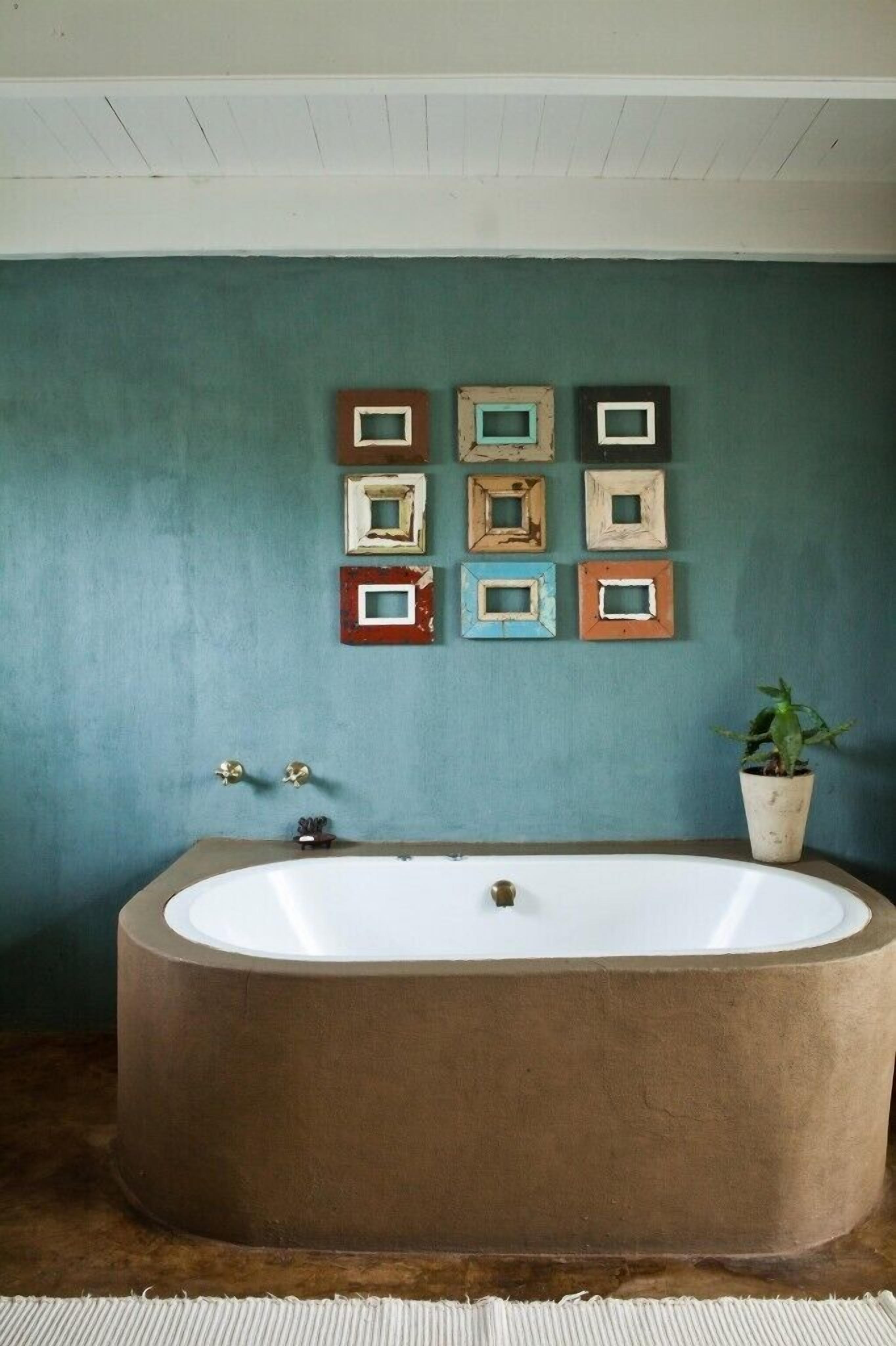 A bathroom with a large bathtub, a wall-mounted mirror, and a potted plant.