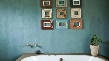 A bathroom with a large bathtub, a wall-mounted mirror, and a potted plant.