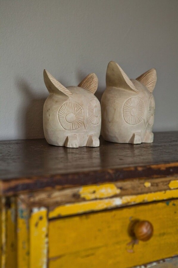 Deux figurines d’animaux sculptées dans du bois, posées sur une surface en bois, avec un tiroir jaune en dessous.