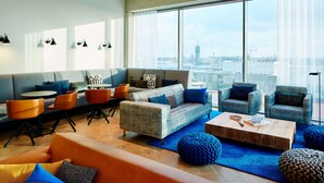 Una sala de estar moderna con un sofá, sillones, una mesa de centro y vistas de la ciudad a través de amplias ventanas.