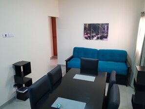 A modern living room with a blue sofa, a black dining table, and a small black side table. - Marazul (San Antonio de Padua)