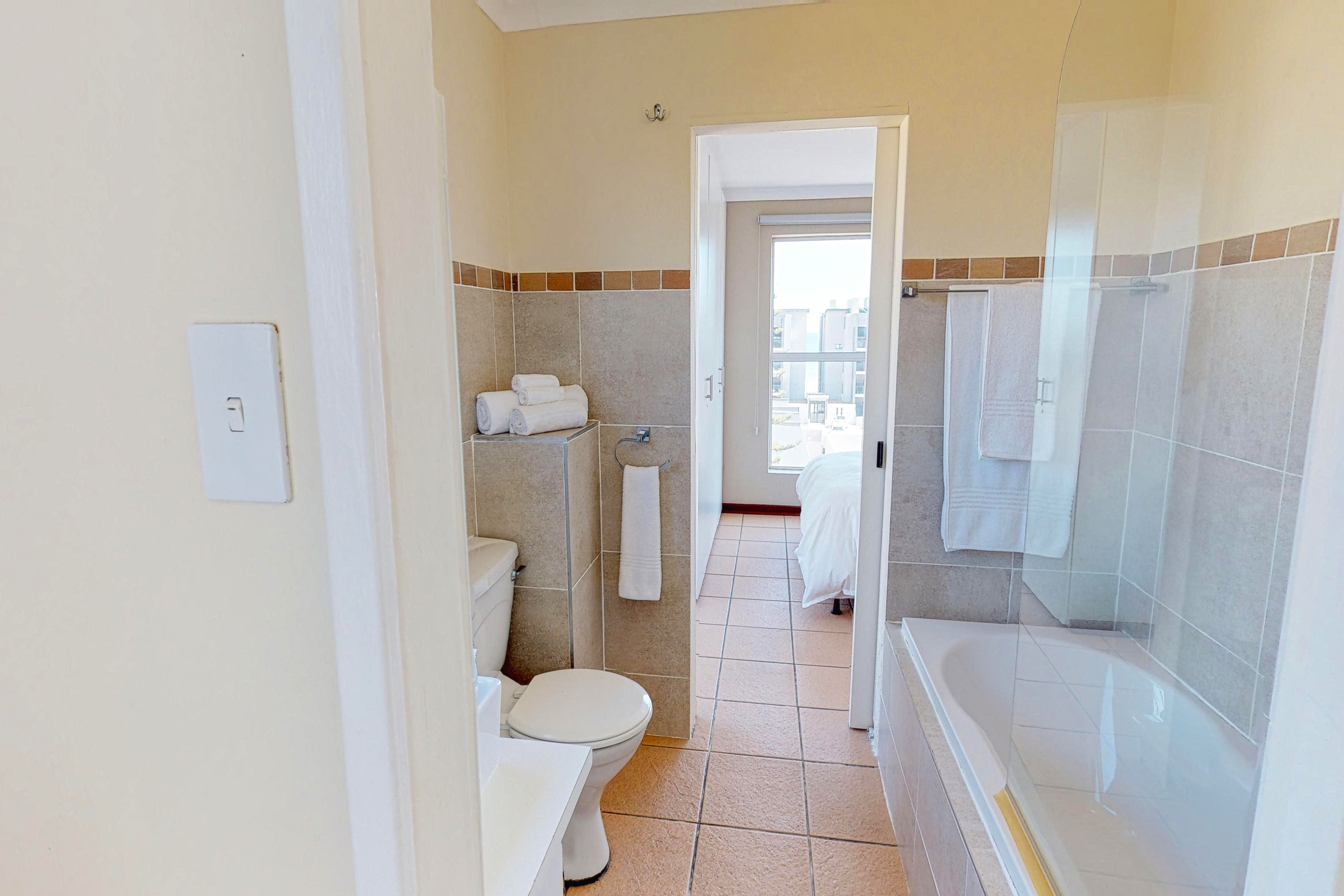 A bathroom with a toilet, sink, and bathtub. There is a towel rack with towels and a shower curtain.