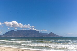 A beach with waves, a mountain, and a clear sky. - Mont Blu Condo (Cape Town)