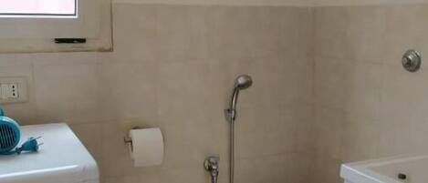 Un baño pequeño con lavadora, inodoro y ducha.