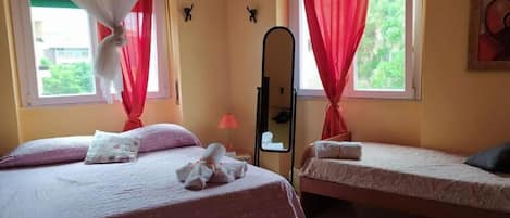 A hotel room with two beds, a mirror, and red curtains.