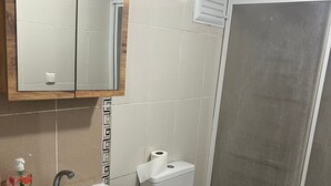 A bathroom with a white sink, a mirror, a toilet, and a shower enclosure. - Safrangold pansiyon (Karabük)