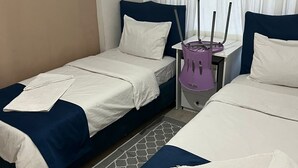 A hotel room with two beds, a small table with a purple chair, and a window with white curtains. - Safrangold pansiyon (Karabük)