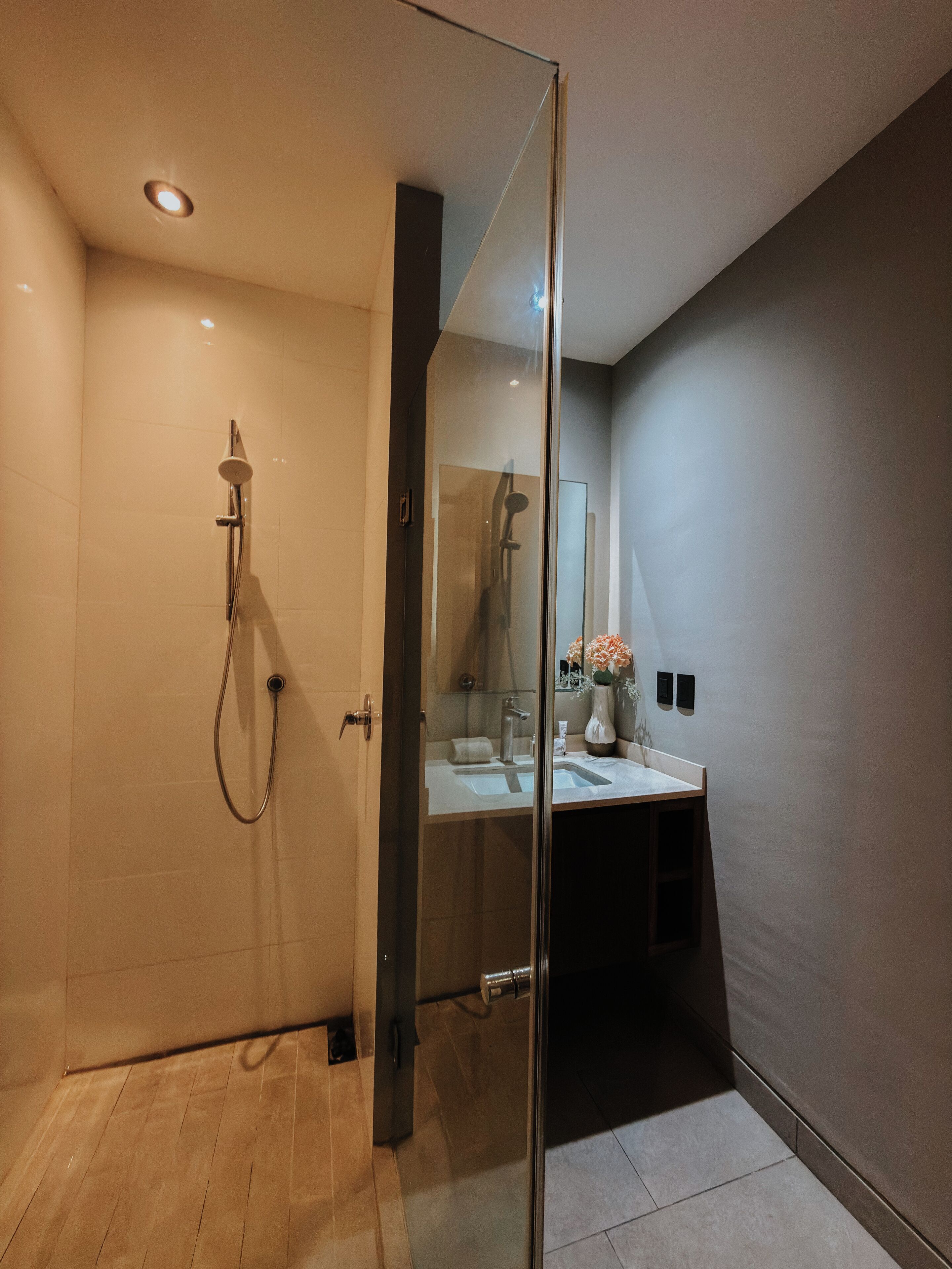 A modern bathroom with a glass shower enclosure, a vanity with a mirror, and a sink.