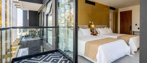 A modern hotel room with two beds, a glass wall, and a geometric patterned floor.