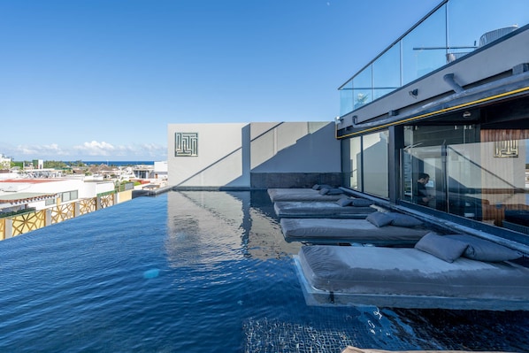 An infinity pool with lounge chairs and a view of the city.