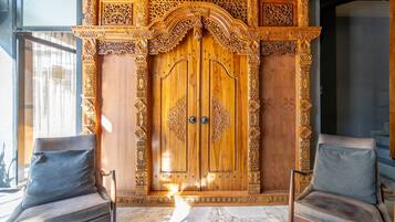 A wooden door with intricate carvings, flanked by two leather chairs with cushions.