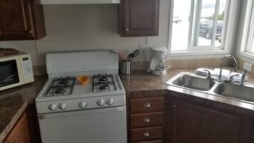 Una cucina con fornello, microonde, macchina per il caffè e lavello.