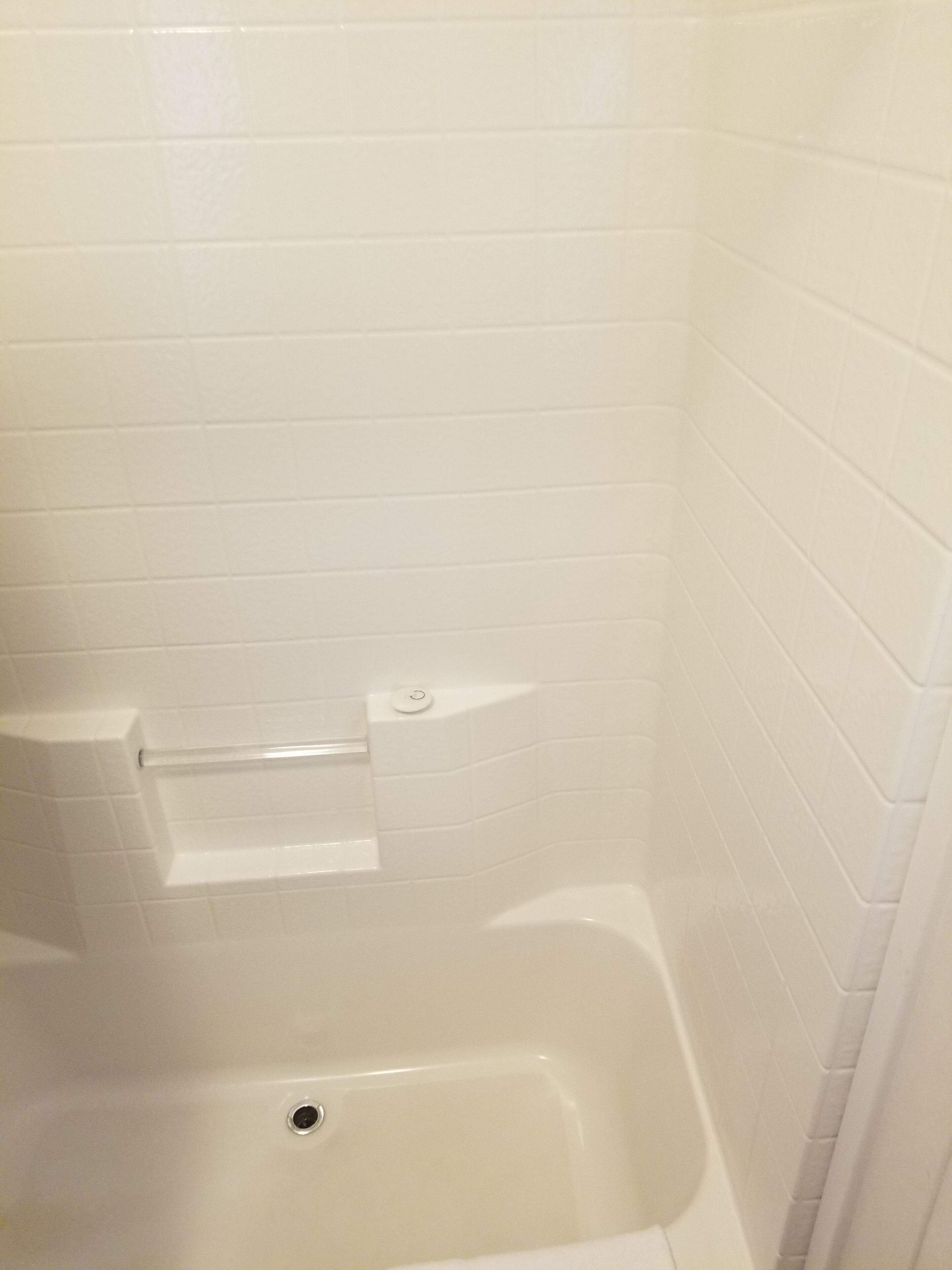 A bathroom with white tiled walls and a bathtub.
