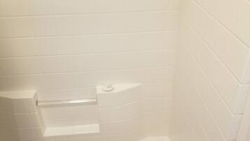 A bathroom with white tiled walls and a bathtub.