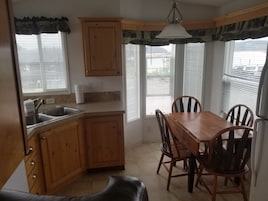 Una cocina con armarios de madera, un lavamanos y una mesa de comedor con sillas.