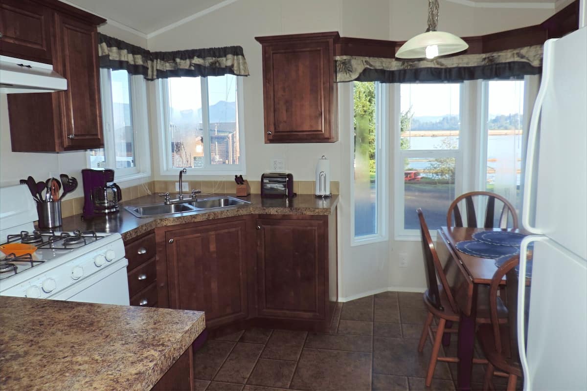 A kitchen with wooden cabinets, a gas stove, a sink, and a dining area with a table and chairs.