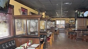 Un interior de restaurante con cabinas, mesas y una zona de bar.