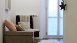A room with a sofa, a small rug, and a sliding glass door leading to a balcony.
