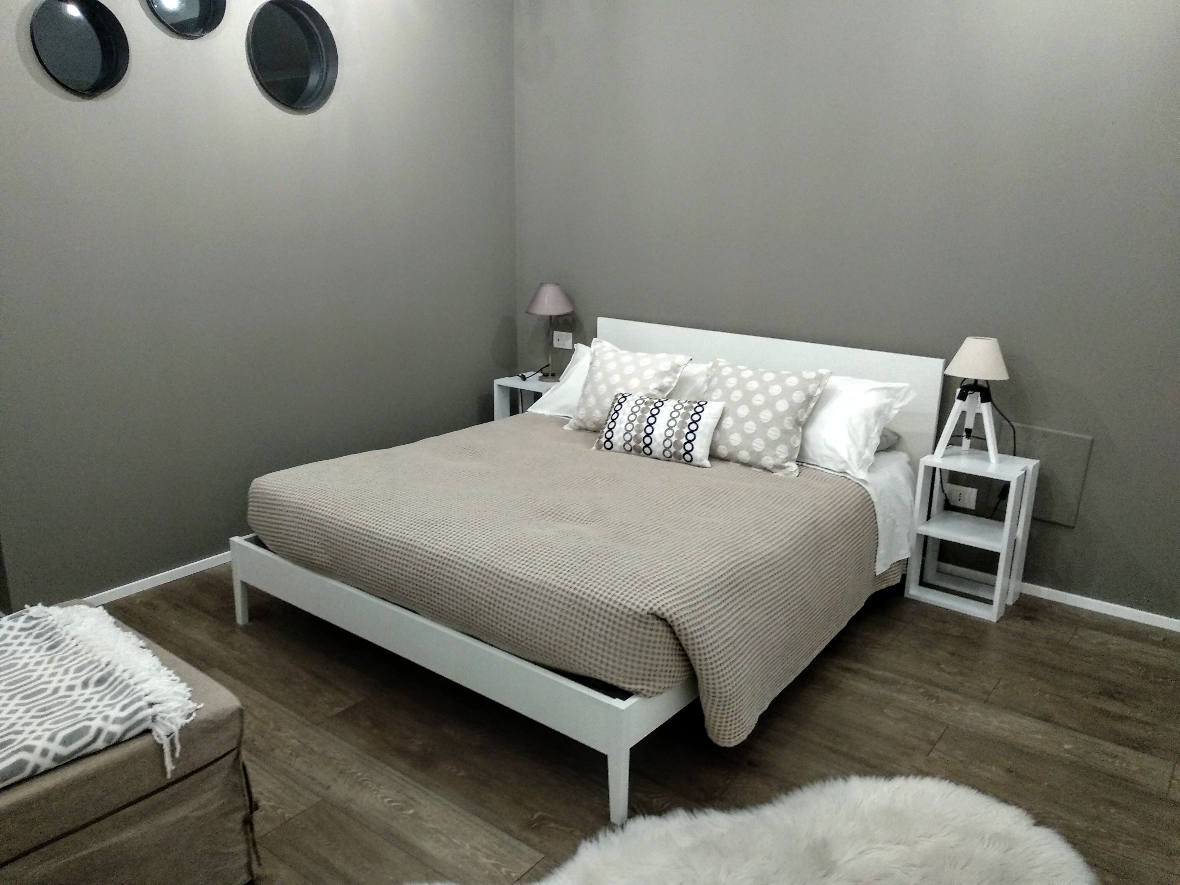 Un dormitorio con cama, mesitas de noche, una lámpara y una pequeña mesa.