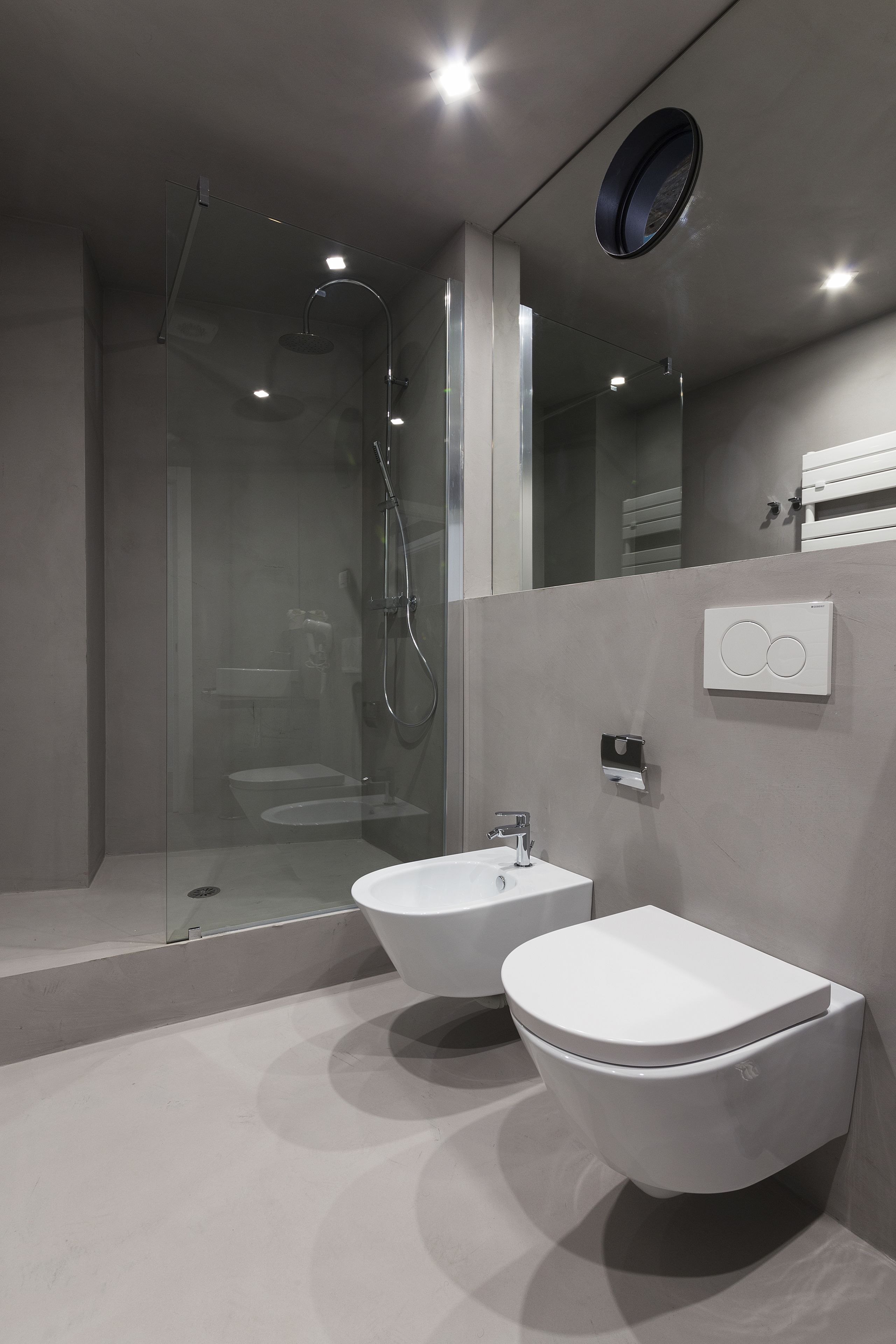 A modern bathroom with a glass-enclosed shower, two sinks, and a toilet.