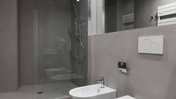 A modern bathroom with a glass-enclosed shower, two sinks, and a toilet.