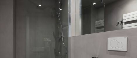 A modern bathroom with a glass-enclosed shower, two sinks, and a toilet.