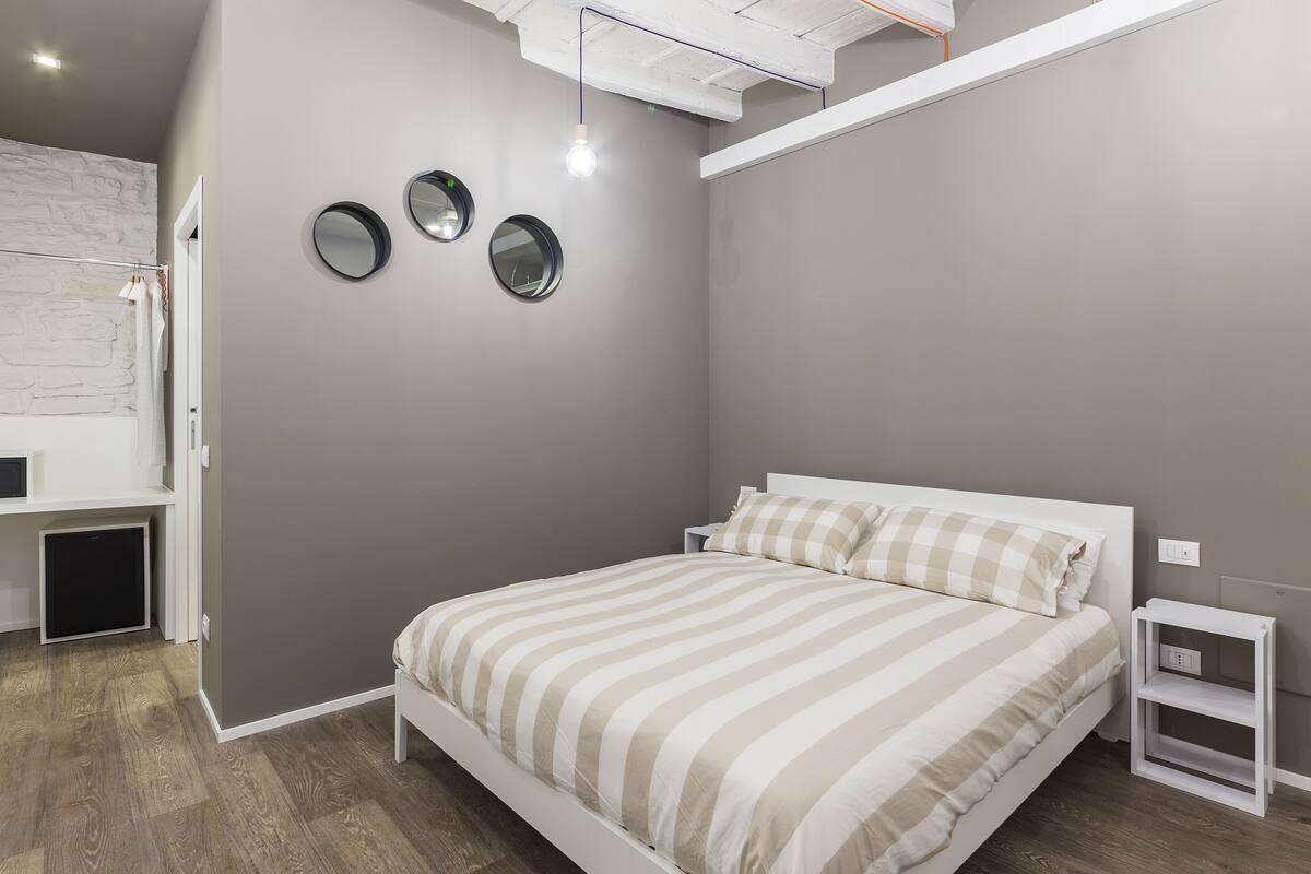 Un dormitorio con una cama, mesitas de noche y un espejo en la pared.