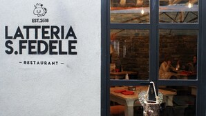 A restaurant sign with the name 'Latteria S. Fedele' and 'EST. 2018' indicating its establishment year.