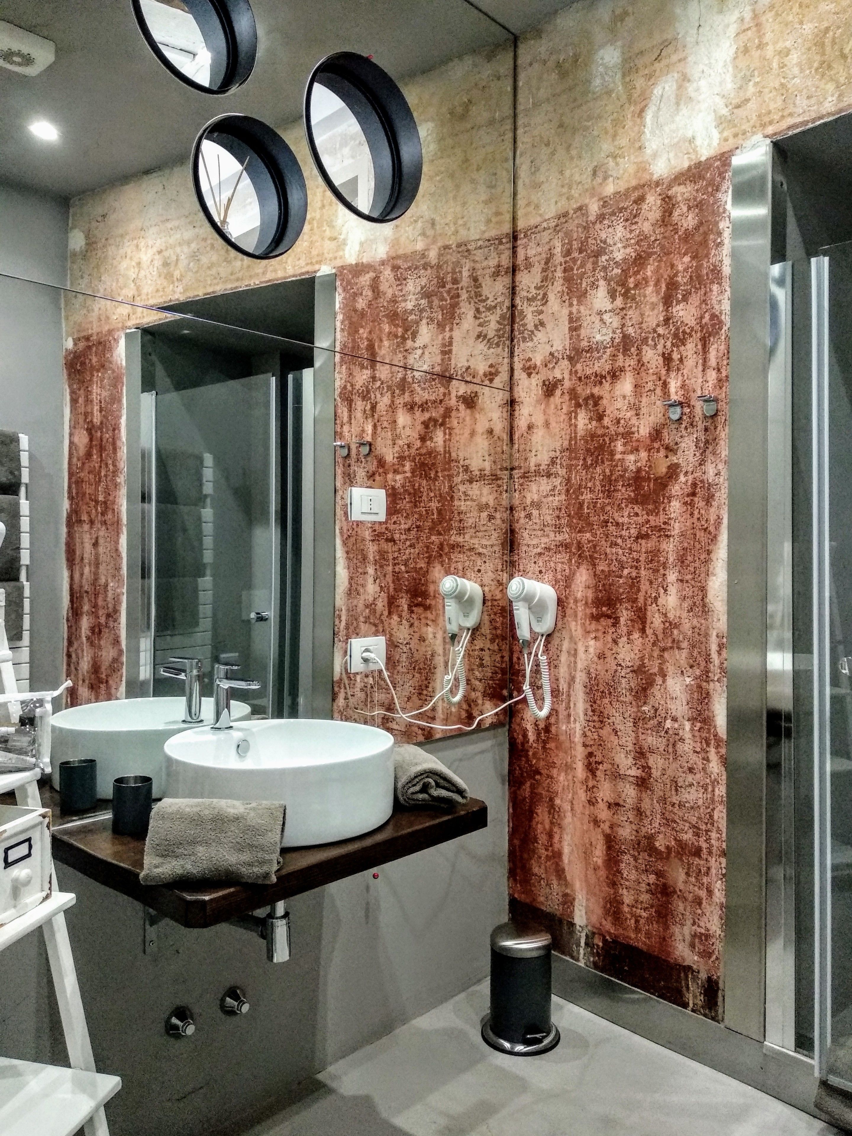 Une salle de bain moderne avec deux lavabos, un grand miroir et des sèche-cheveux fixés au mur.