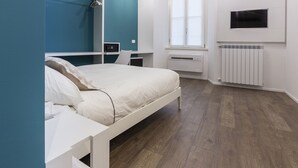 A modern bedroom with a bed, bedside tables, a TV, and a window.