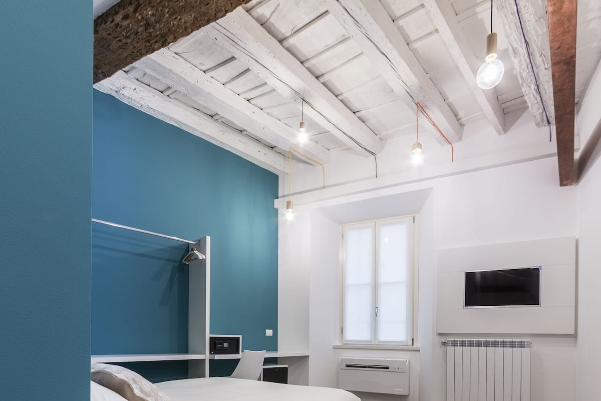 Un dormitorio moderno con cama, mesitas de noche, televisor y ventana.