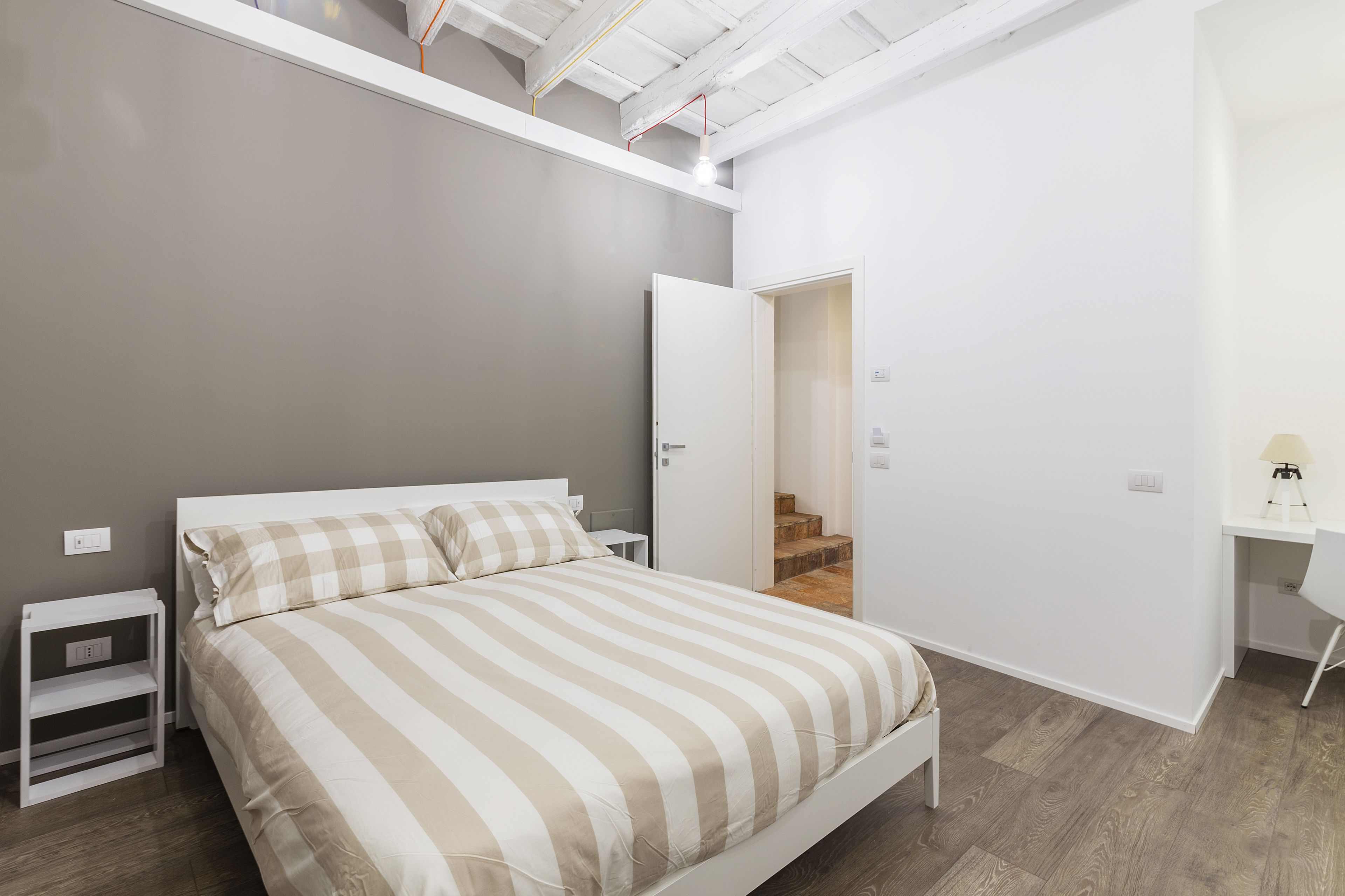 Un dormitorio moderno con cama, escritorio y escalera que lleva a un nivel superior.