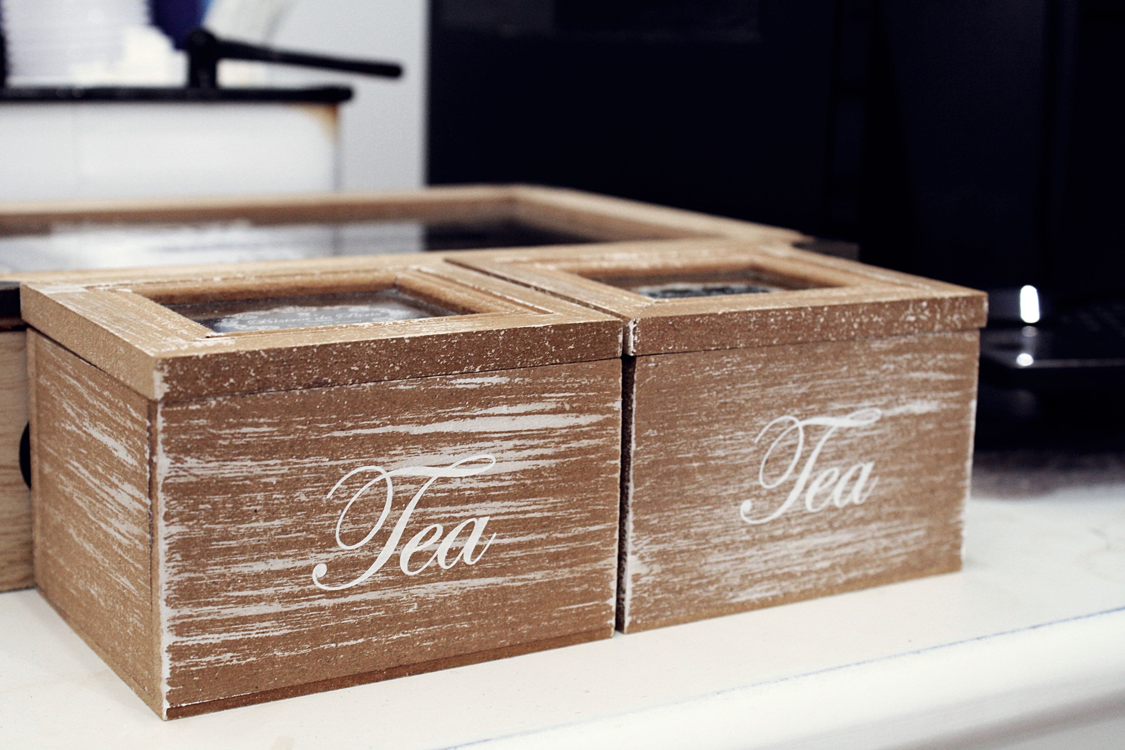 A rustic wooden box with compartments labeled "Tea".