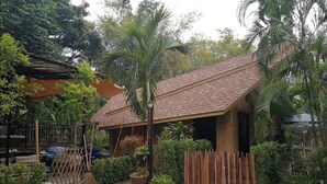 A rustic house with a sloped roof, surrounded by lush greenery and a gravel driveway. - Brookhouse at Khaoyai (Pak Chong)