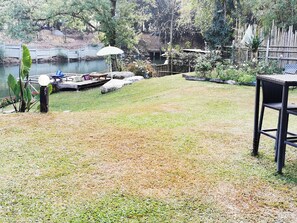 A grassy backyard with a dock, a white umbrella, and a black chair. - Brookhouse at Khaoyai (Pak Chong)