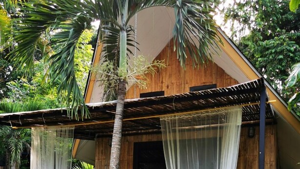 A wooden house with a covered porch, two chairs, and a potted plant. - Brookhouse at Khaoyai (Pak Chong)