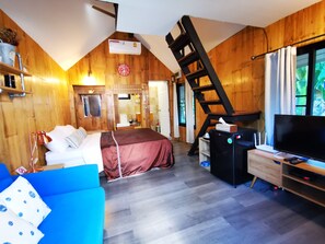 A cozy room with a bed, a blue sofa, a TV, and a wooden ladder. - Brookhouse at Khaoyai (Pak Chong)