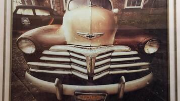 A vintage car with a prominent front grille and emblem, parked in front of a building with windows and a brick facade.
