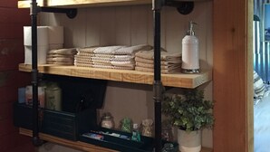 A wooden shelf unit with folded towels and a small potted plant.