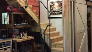 A wooden staircase with a metal handrail leading to a loft area. A framed picture hangs on the wall above the stairs.