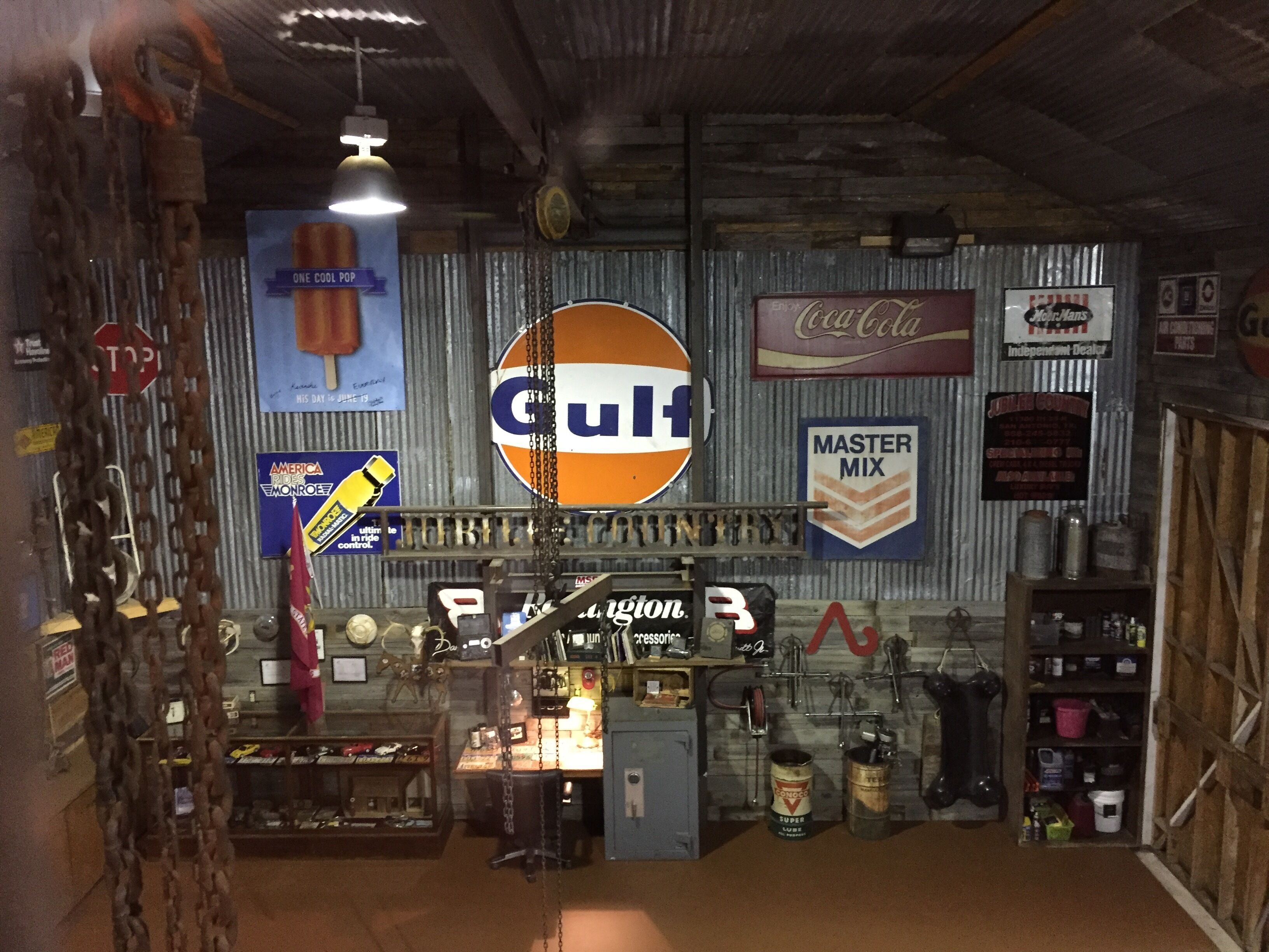 A vintage-themed interior with a prominent Gulf logo, a Coca-Cola sign, and a Master Mix sign.