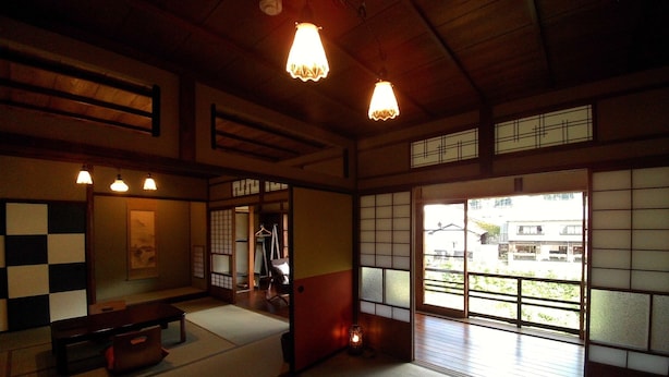 A traditional Japanese room with tatami flooring, shoji screens, and a low wooden ceiling.